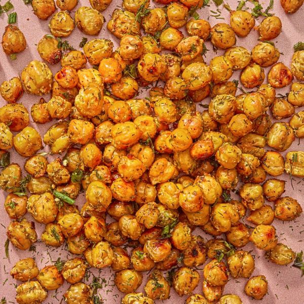 A batch of roasted chickpeas garnished with herbs arranged on parchment paper Credit: Ali Redmond