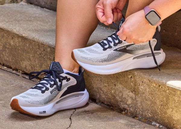 Person tying Brooks running shoes on their feet while sitting on outdoor steps Credit: EatingWell/Nick Simpson