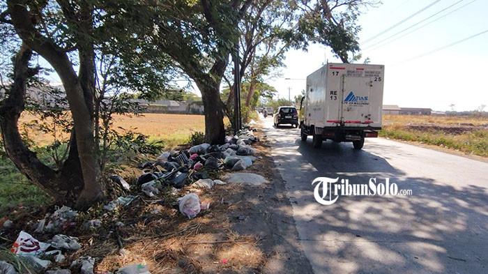 TUMPUKAN SAMPAH - Penampakan tumpukan sampah yang berada di pinggir jalan Adi Sumarmo, Kecamatan Colomadu, Kabupaten Karanganyar, Sabtu (5/9/2026). Berkarung-karung sampah menumpuk di bawah pepohonan yang berjajar di pinggir jalan. Kantong plastik berwarna hitam, putih, hingga beberapa kantong berwarna lainnya terlihat berserakan dan menggunung di antara batang pohon.