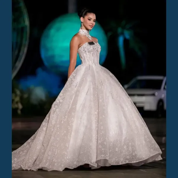 This look of Johari Mol Dominguez is like that of a Barbie doll. She is wearing a white colored heavy flared flowy gown, which has a corset off shoulder top. To complete her look, she has carried a statement necklace which makes the look royal. He has completed his look with a sleek one.