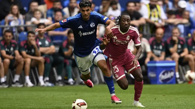 Bek asal Turki milik Schalke bernomor punggung 43, Mertcan Ayhan (kiri), dan penyerang asal Pantai Gading milik Real Madrid bernomor punggung 25, Yan Diomande, berebut bola dalam pertandingan persahabatan pramusim antara FC Schalke 04 dan Real Madrid di Gelsenkirchen, Jerman bagian barat, pada 16 Agustus 2026. (INA FASSBENDER/AFP)
