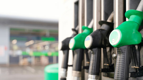 Four filler nozzles, two green diesel fuel nozzles next to black gas nozzles at fuel station, staggered between gas and diesel nozzles