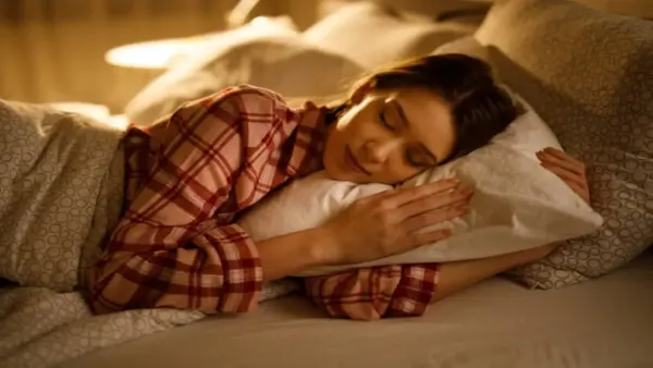 A woman sleeping peacefully in bed while hugging a pillow, highlighting the importance of good sleep and sleep hygiene.
